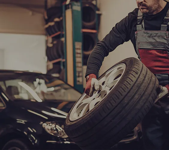 man carrying tyre in workshop