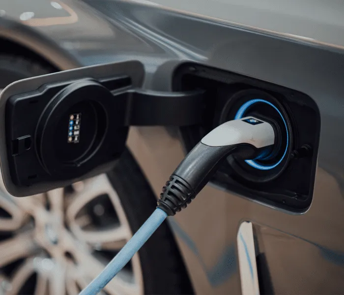 Close-up of an electric vehicle being charged, with a charging cable connected to the vehicle's charging port.